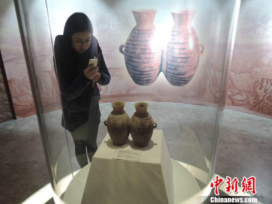 图为参观者拍摄出土于大河村遗址的彩陶双连壶。此为仿品，真品现馆藏于河南博物院，为国宝（韩章云/摄）